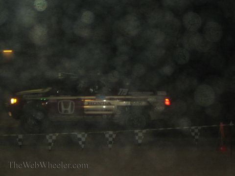 1990 Ford Bronco - Honda-sponsored off-road race truck numbered 779 passes behind checkered flags through dusty night haze.