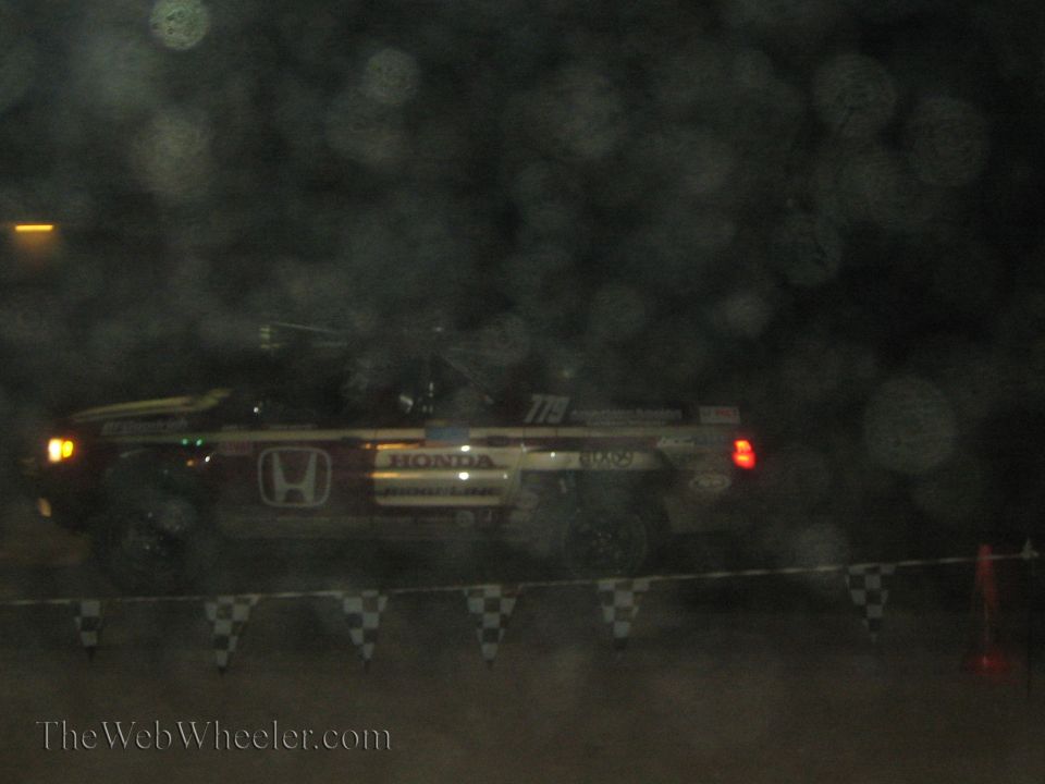 Honda-branded off-road race truck at night through haze