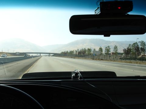 1993 Ford Taurus - Driving on a highway with mountains in the background. A radar detector is visible on the windshield.