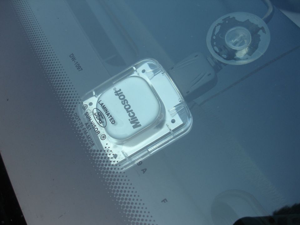 Microsoft device with Ford logo and 'LAMINATED SUN-VISOR' text attached to a car windshield