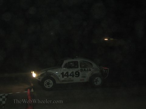 1990 Ford Bronco - white Volkswagen Baja Bug racer marked 'BAJA' and number 1449 sits with its headlight glowing in the dark.