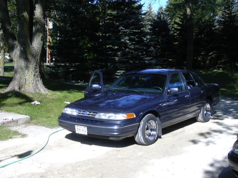 1996 Ford Crown Victoria - A dark blue 1996 Ford Crown Victoria sedan is parked outside with the driver's door ajar.