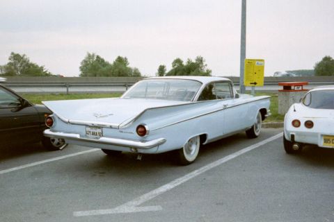 1991 Ford Crown Victoria - A light blue 1959 Buick LeSabre is parked next to other vehicles in a lot.