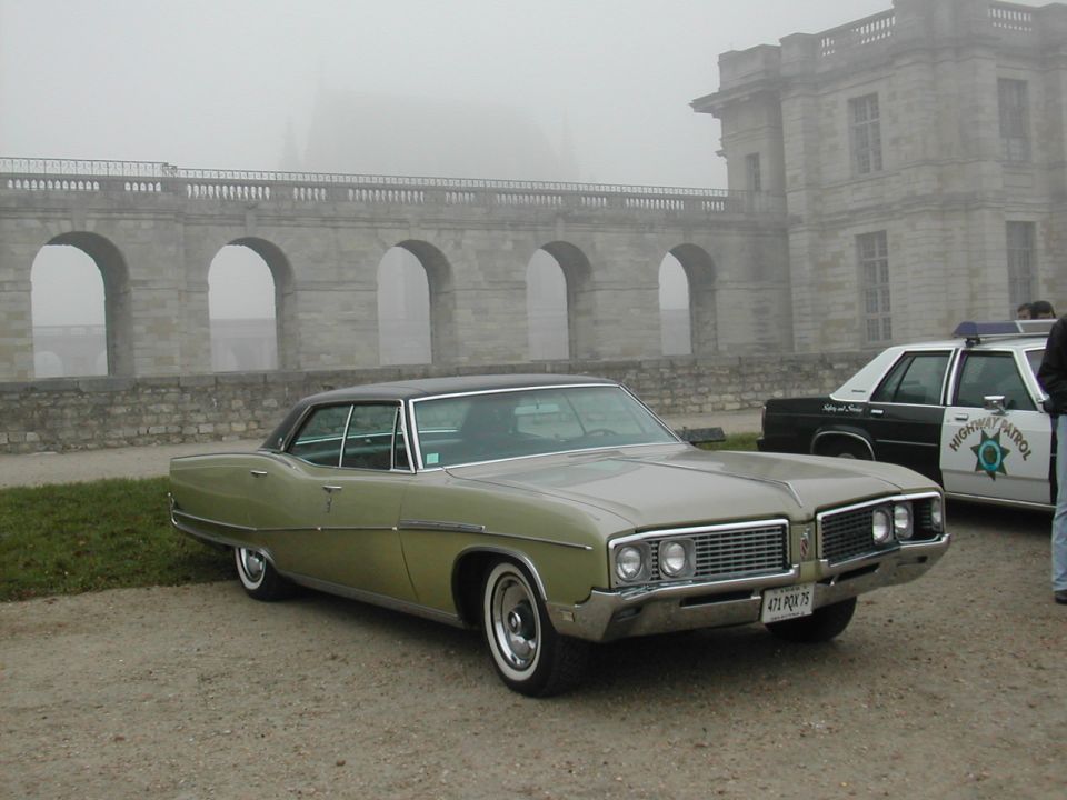 Green 1967 Buick LeSabre 4-door sedan parked next to a highway patrol car