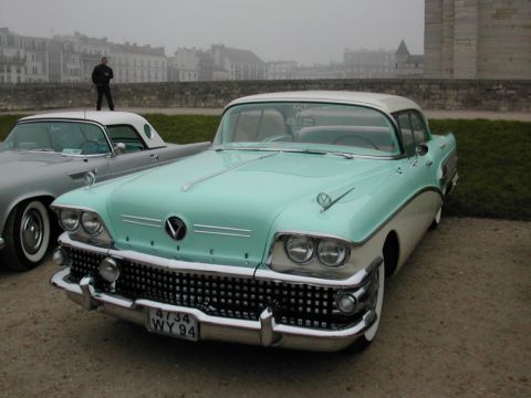 1991 Ford Crown Victoria - A teal and white 1958 Buick Century coupe is parked next to another vintage car, with a person standing on its roof.