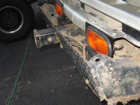 1977 Ford F-150 - Close-up of a vehicle's rear bumper, showing the trailer hitch and amber lights.
