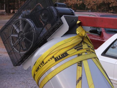 1965 Ford Mustang - An air compressor tank is secured with yellow Allied straps, with a red tow arm and a white vehicle visible in the background.