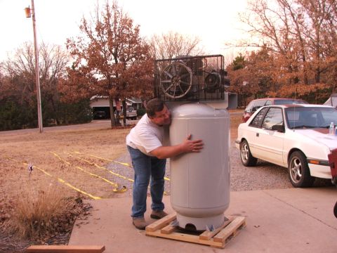 1965 Ford Mustang - A man hugs a large air compressor tank next to a white coupe with a red hood stripe.