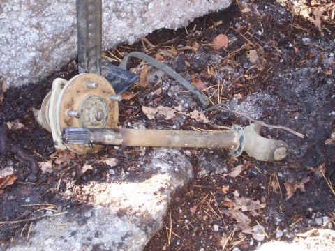 1989 Ford F-350 - This appears to be a driveshaft component lying on the ground with debris.