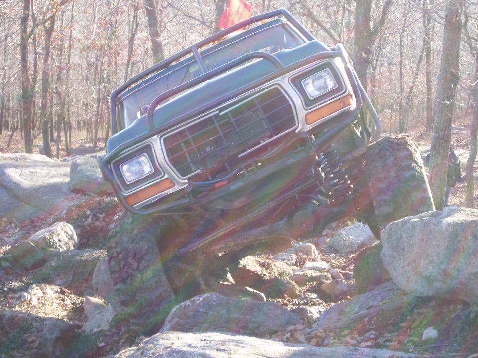 Green 1979 Ford F-Series truck with off-road modifications navigating rocks