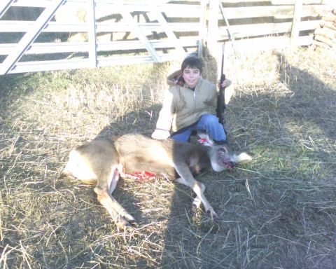 1989 Ford Bronco - A young hunter poses with his kill, a deer lying on the ground.