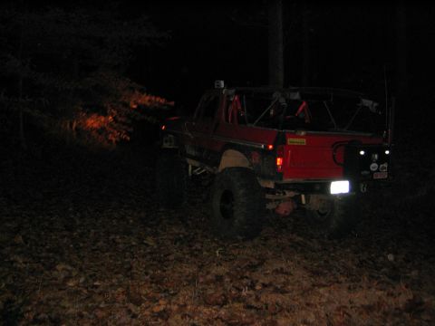 1979 Ford Bronco - Red Ford Bronco parked on a wooded path at night, showing its rear and side profile.