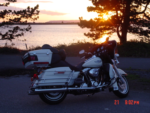 White touring motorcycle parked by a lake at sunset