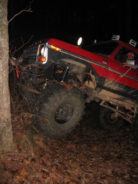 1979 Ford Bronco - A red 1979 Ford Bronco navigates a steep, wooded terrain at night.