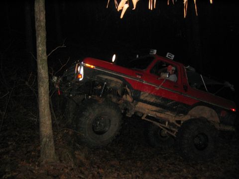 1979 Ford Bronco - Red Bronco navigating rough terrain in the dark, driver at the wheel.