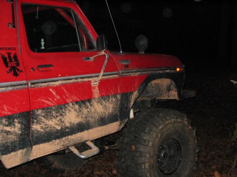 1979 Ford Bronco - A muddy red 1979 Ford Bronco is seen at night, equipped for off-road use.
