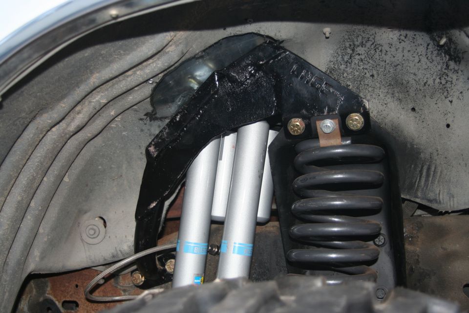 Front suspension part with dual shocks and coil spring, visible "SUPERMOTORS" text