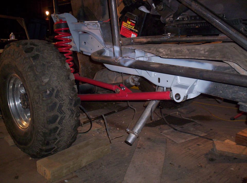 Off-road vehicle chassis with large tire, red suspension, and exposed frame