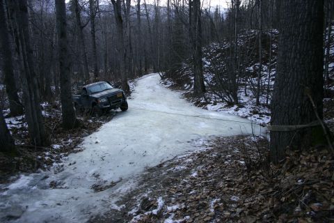 2003 Jeep TJ - Truck stuck on an icy road in a wooded area, possibly needing a tow.