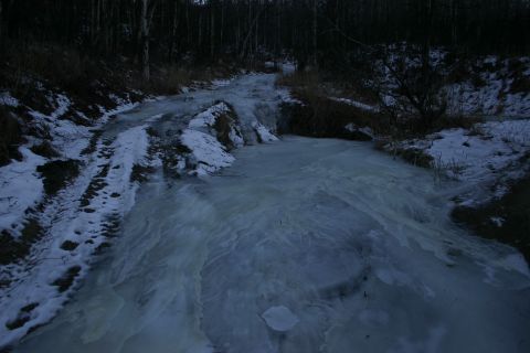 2003 Jeep TJ - A frozen, partially snow-covered road winds through a dark forest.