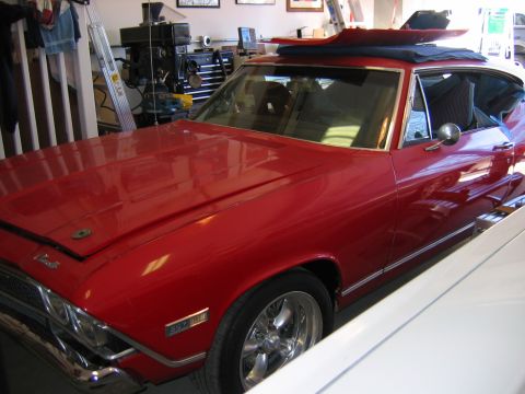 1985 Ford LTD Crown Victoria - A red 1969 Chevrolet Chevelle SS coupe is parked in a garage next to another vehicle.