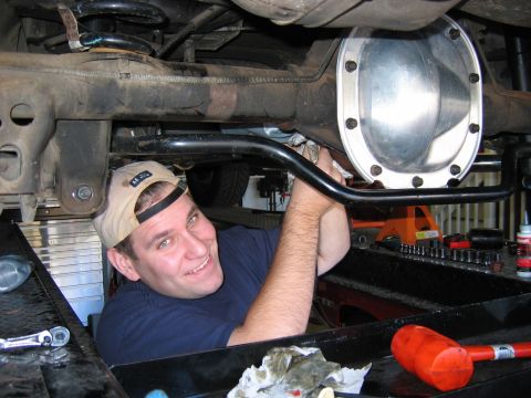1985 Ford LTD Crown Victoria - Mechanic installs a new cover on a car's rear differential assembly.