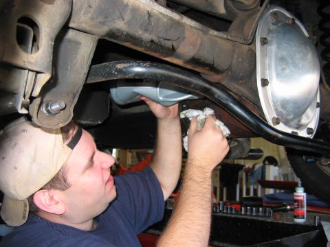 1985 Ford LTD Crown Victoria - A person is performing maintenance on the rear differential of a vehicle, likely changing the fluid.