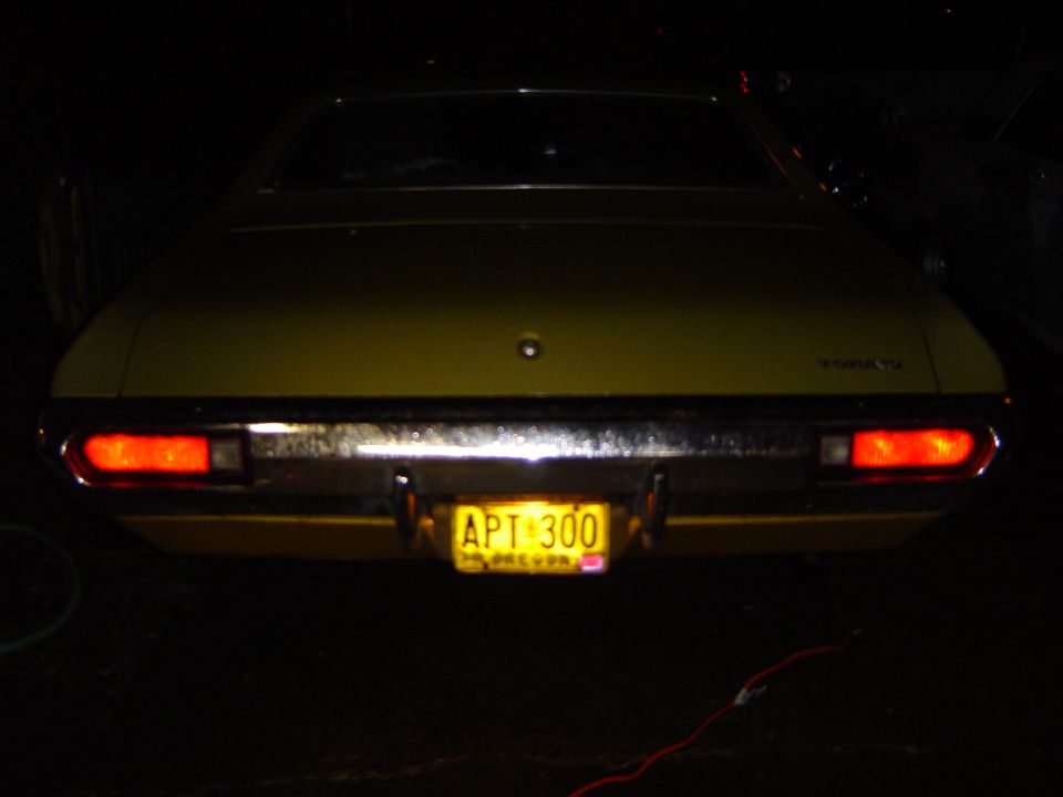 Rear view of yellow Ford Torino at night with Oregon plate APT 300 illuminated