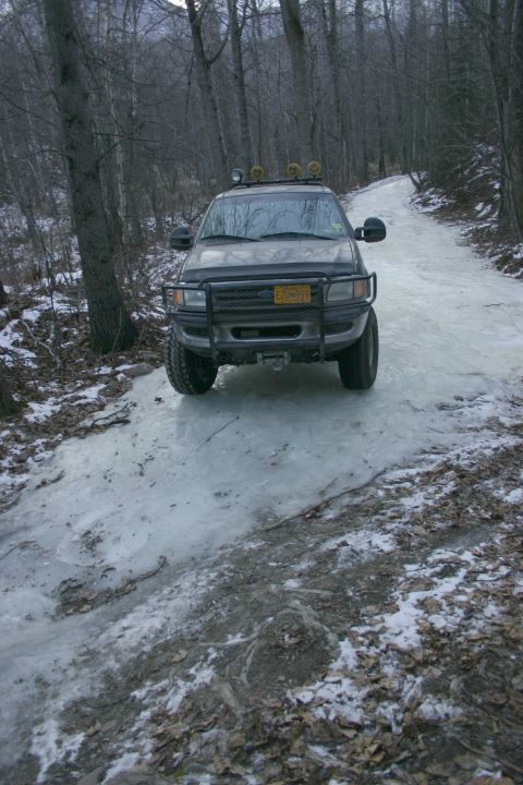 2003 Jeep TJ - Ford F-150 navigating a slippery, icy road through a wooded area.
