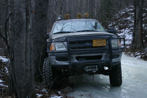2003 Jeep TJ - This Ford F-150, likely from the late 1990s, is parked on a slippery, icy surface in a wooded area.