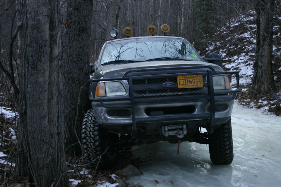 Gray Ford F-150 with bull bar and winch on icy road, front view