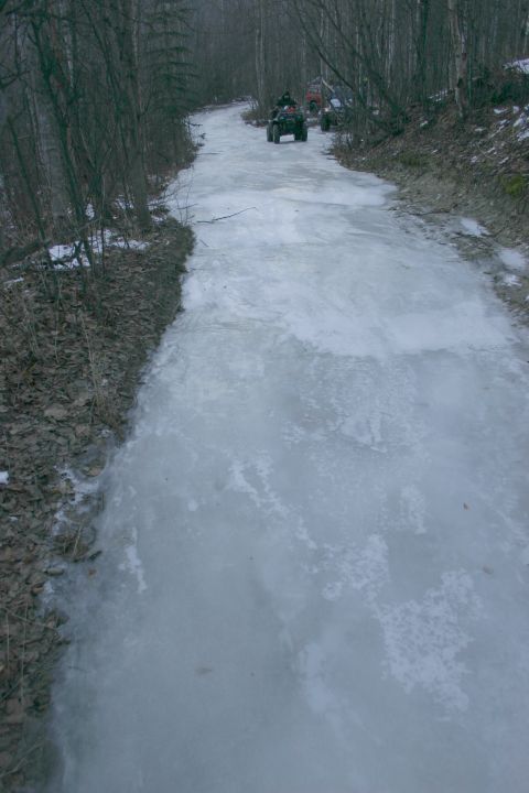 2003 Jeep TJ - Multiple ATVs navigate an icy path through a wooded area during winter.