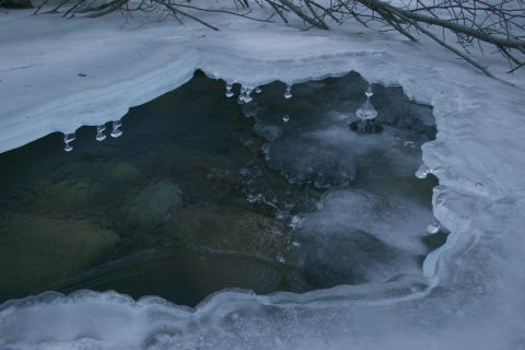 2003 Jeep TJ - Icicles hang from the edge of a frozen stream, with dark water flowing beneath.