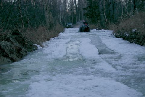 2003 Jeep TJ - Two ATVs navigate a challenging icy and snowy path through a forest during winter.