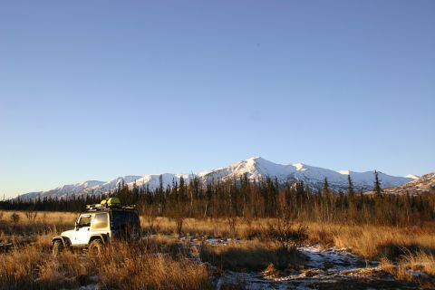 2003 Jeep TJ - A white Jeep Wrangler sits in a field of dry grass with snow-capped mountains in the distance.