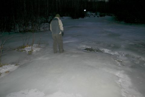 2003 Jeep TJ - A person stands on a frozen body of water surrounded by trees in a dimly lit, wintery landscape.