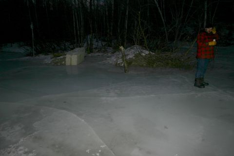2003 Jeep TJ - A person stands on a frozen surface in a dark, wooded area, illuminated by artificial light.