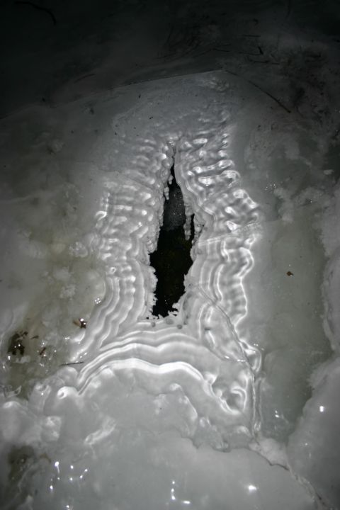 2003 Jeep TJ - An unusual ice formation with rippled patterns covers a dark opening in the ground.