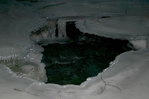 2003 Jeep TJ - A hole in the ice reveals dark, flowing water, with icicles hanging from the frozen edges.