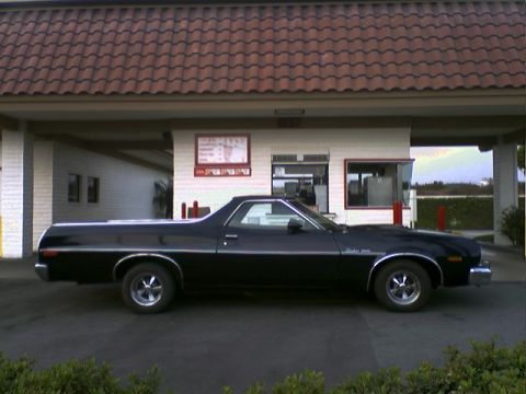 1973 Ford Ranchero - Side view of a black 1973 Ford Ranchero, identified by its body style, parked near a drive-thru establishment.