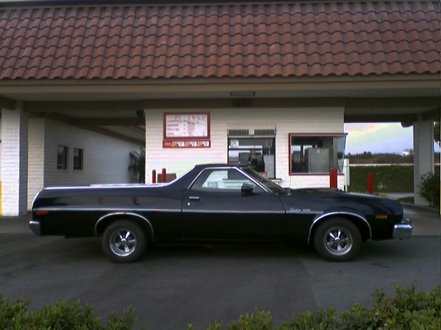 Black 1973 Ford Ranchero parked outside a building with a drive-thru window