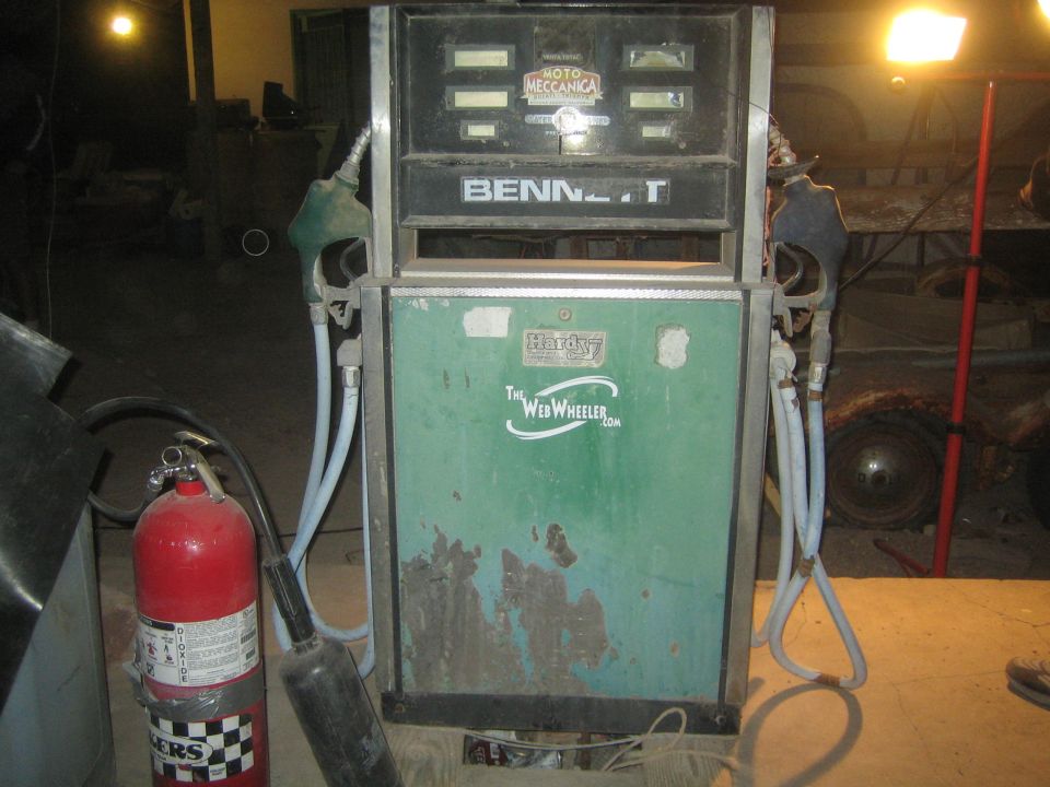 Old green Bennett fuel pump in a dim garage with a red fire extinguisher