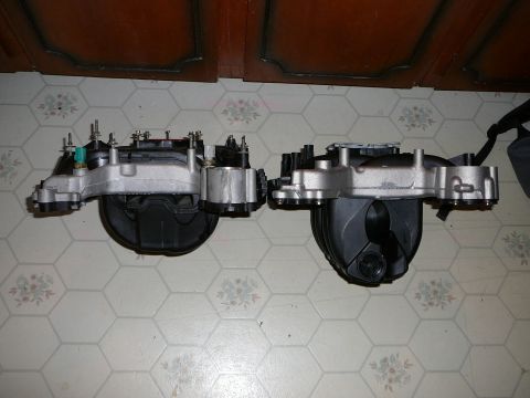 1997 Mercury Grand Marquis - Two composite intake manifolds with cast aluminum end rails set side by side on a hexagonal-tile floor for comparison, showing the differin…