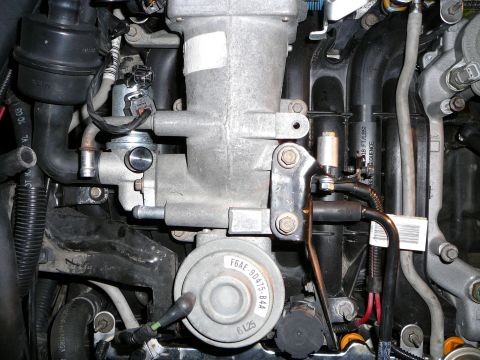 1997 Mercury Grand Marquis - Overhead view into an engine bay showing the cast aluminum throttle body and upper intake elbow, with the EGR vacuum regulator disc stamped…