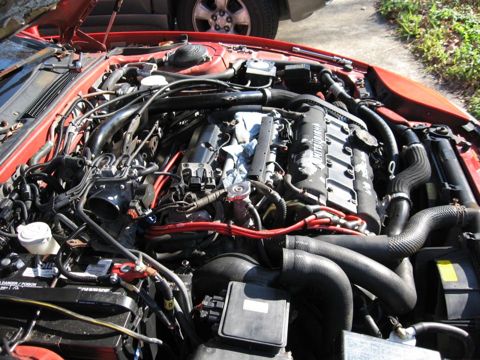 Overhead view of red car's Mitsubishi V6 engine bay with red plug wires