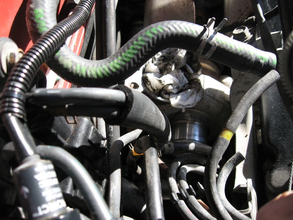 Engine bay close-up showing hoses, clamps, and a turbocharger with a rag stuffed into it