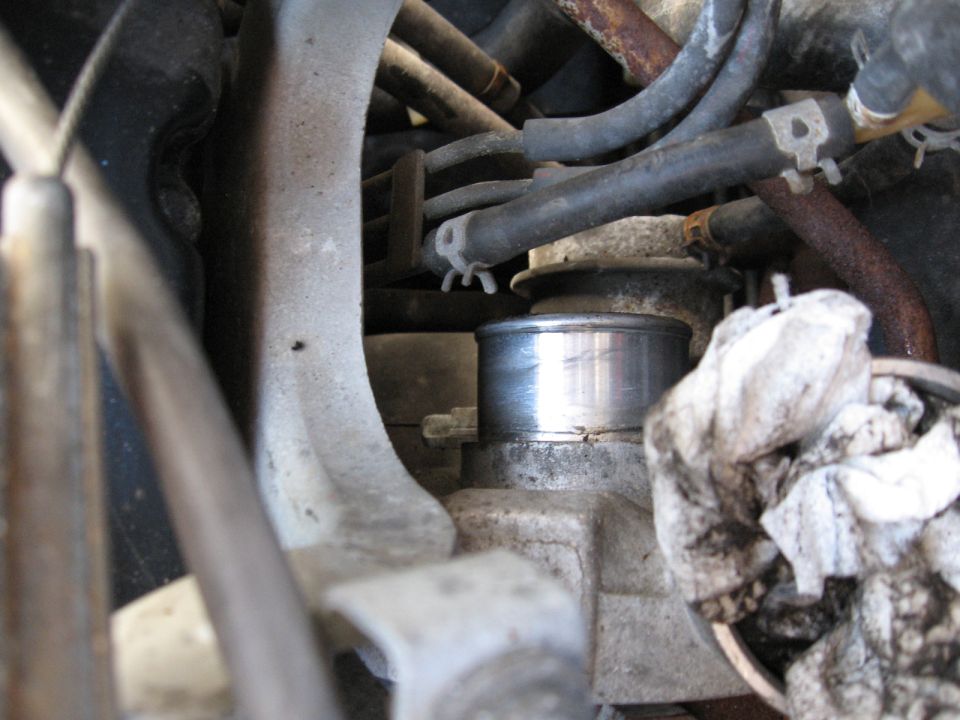 Close-up of engine components with hoses and a silver cylinder