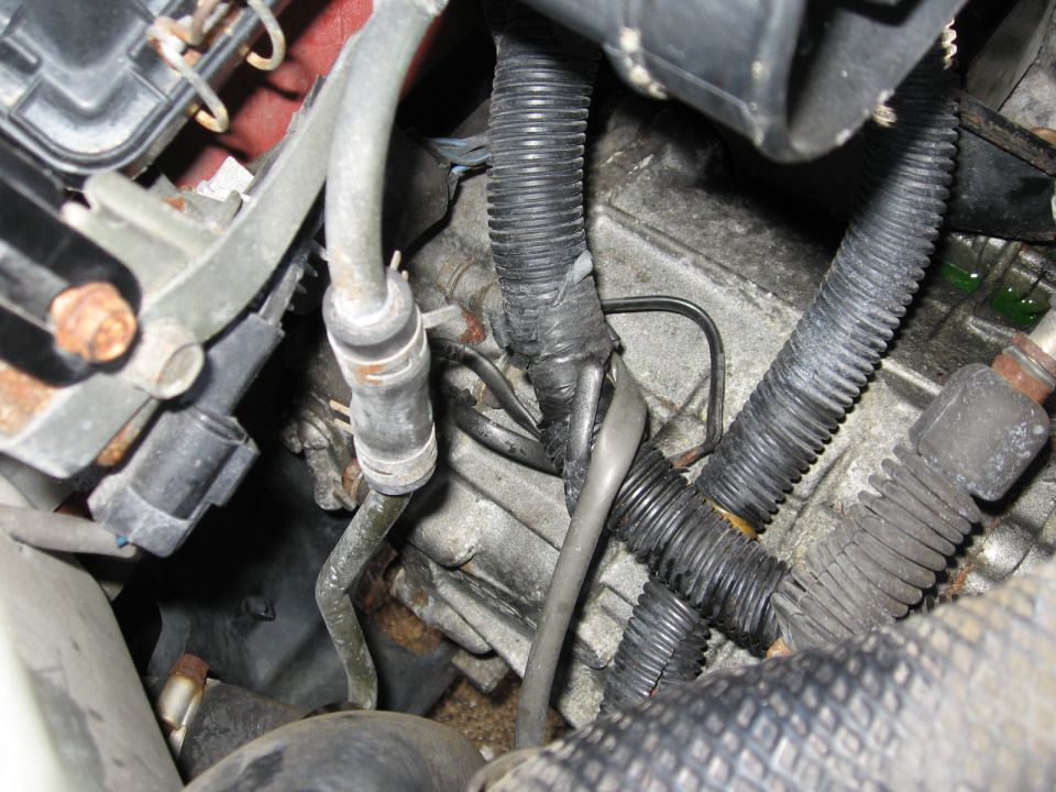close-up of engine bay with various wires, hoses, and metal components visible