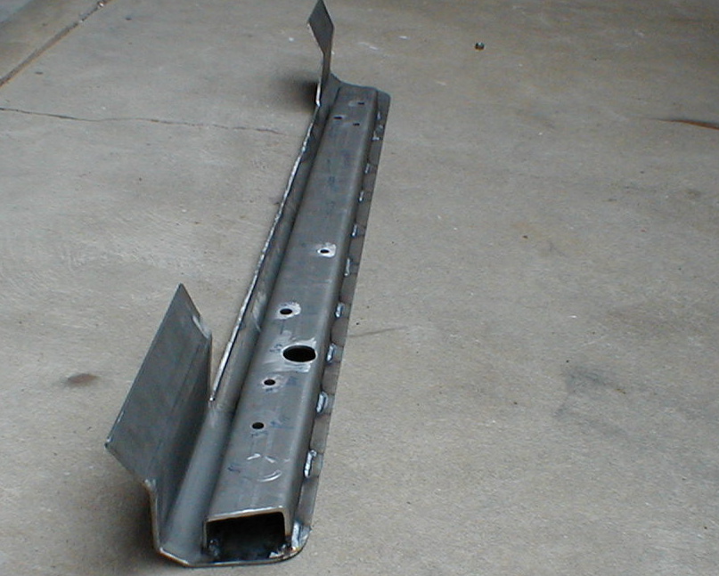 Fabricated bare steel rocker rail with plug welds and drilled holes on concrete floor