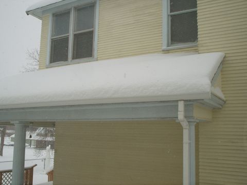 1990 Ford Bronco - A house exterior is covered in snow during a winter storm, with a white downspout visible.